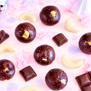 banana chocolate chip protein balls sits on a pink party-themed surface with scattered chocolate pieces and banana lollies