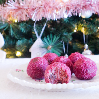 Cherry Delight Protein Balls on a white plate with a decorated tree in the background.