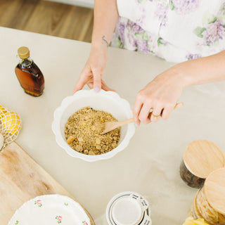 Person mixing protein ball mix in a bowl on a kitchen counter with various items around