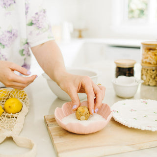 Person preparing protein balls in a kitchen with various items on a counter.