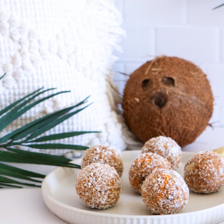 Mango Cheesecake balls on a plate with a coconut in the background