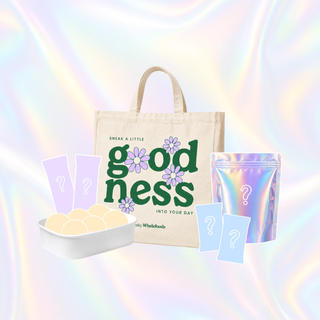 A tote bag set with pastel mystery snack items, including a beige tote bag with green and purple 'goodness' text, a holographic pouch, and pastel snack boxes and cards, all on a pastel iridescent background.