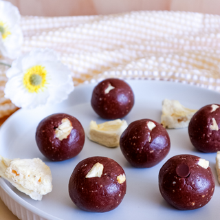 Pineapple Chocolate protein balls on a white plate with a decorative flower. 