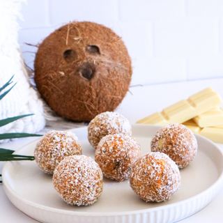 Mango Cheesecake Protein balls on a plate with a coconut in the background