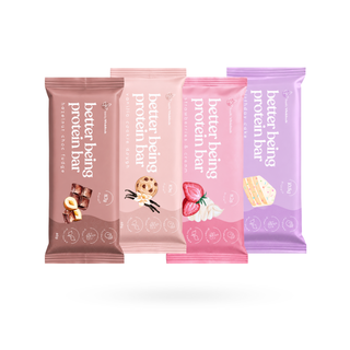 Four packaged protein bars in different flavours arranged in a row on a white background: Hazelnut choc fudge , vanilla cookie dough, strawberry cream, and birthday cake flavours. The packaging features pastel colors.