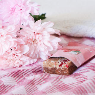 Pink flower bouquet with a chocolate bar and pink packaging on a checkered tablecloth