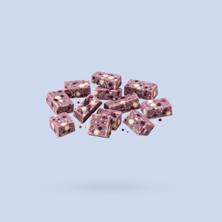 A cluster of purple berry protein bars with white chocolate chips, floating against a solid light blue background.