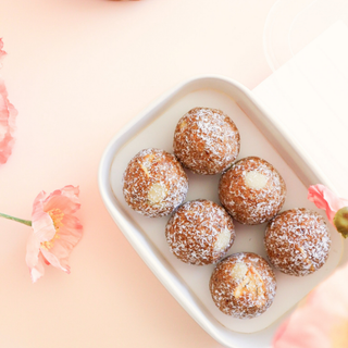 6 Carrot Cake Protein Balls in a white container with pink flowers in the background
