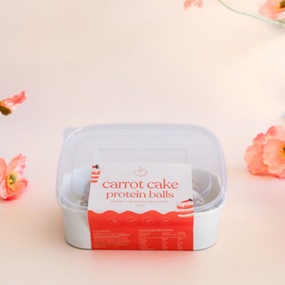 Container of carrot cake protein balls on a light background with flowers
