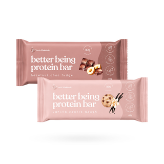 Two packaged protein bars on a clean white background. The top bar is hazelnut choc fudge and the bottom bar is vanilla cookie dough, both from Better Being Protein Bar in cream packaging.