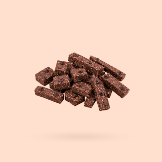A pile of small rectangular jaffa choc chip sneaky seconds, floating against a solid pale peach background.