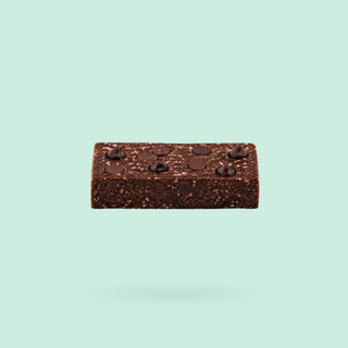 A singular Mint Brownie Nourish Bite with embedded chocolate chips, shown floating against a solid pale mint green background.