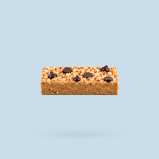 A single peanut butter cookie nourish bite with chocolate chips, shown floating against a solid light blue background.