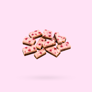 A pile of Raspberry Lamington Sneaky Seconds up against a light pink background