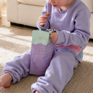 Toddler eating snacks out of Sneaky Seconds packet from Sneaky Wholefoods