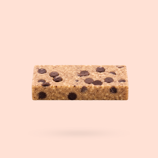 A single Vanilla Cookie Dough Better Being Protein Bar with chocolate chip details, shown floating against a solid pale peach background.