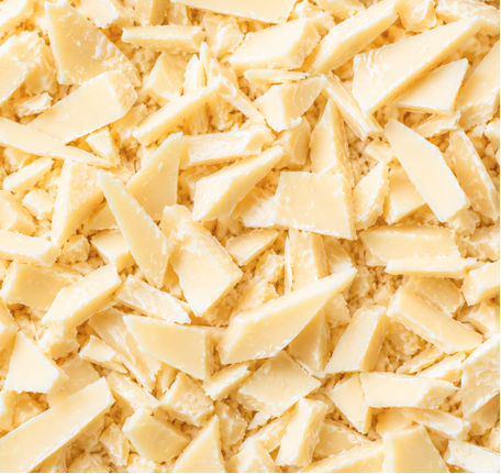 A close-up of irregular pale cream or off-white shavings and chunks filling the frame, with a soft warm tone and no visible product edges or packaging.