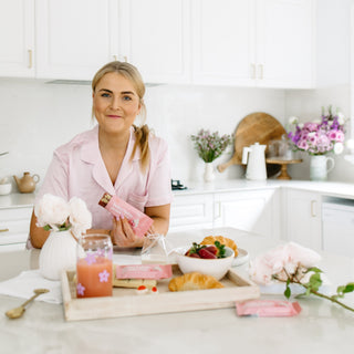 A woman showcasing the open packaging of the Strawberries and Cream Protein Bar, revealing its enticing pink hue and creamy white chocolate chips.