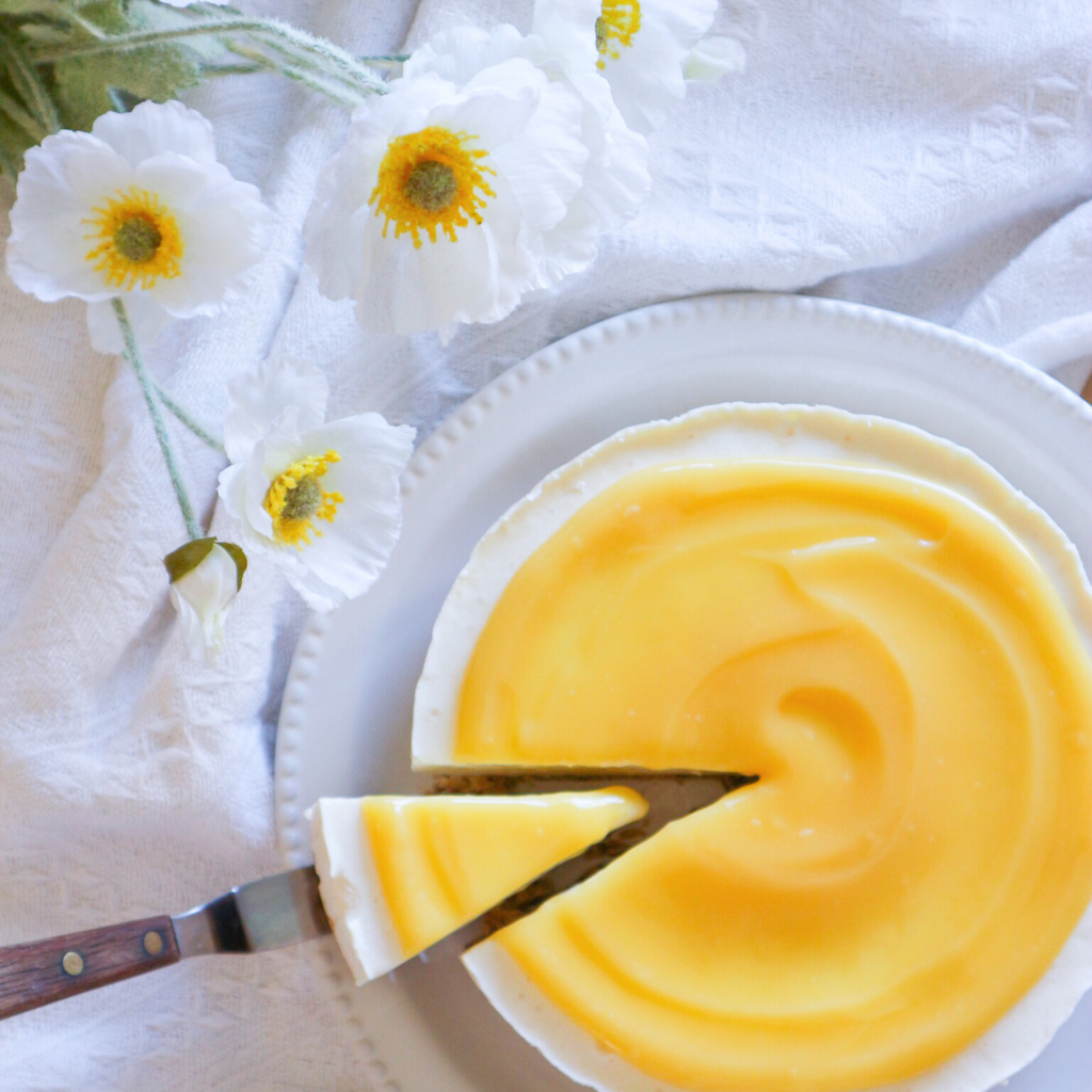 A lemon cheesecake is being placed down on a table then being cut into slices