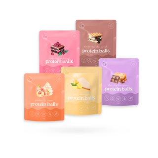 Five stand-up pouches of protein balls in different flavors, arranged in a fan shape on a white background. The pouches are pink, brown, orange, yellow, and purple, each featuring an illustration of a protein ball snack and the text 'protein balls'.