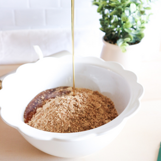 Image of syrup being poured into Sneaky Wholefoods Gingerbread Cookie Dough Protein Ball Mix, showing how to craft your own holiday protein balls with festive flavors of ginger and cinnamon.