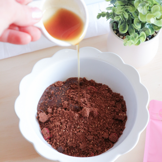 Syrup being added to Raspberry Fudge Brownie Protein Ball Mix – showing how simple it is to prepare plant-based protein snacks at home.